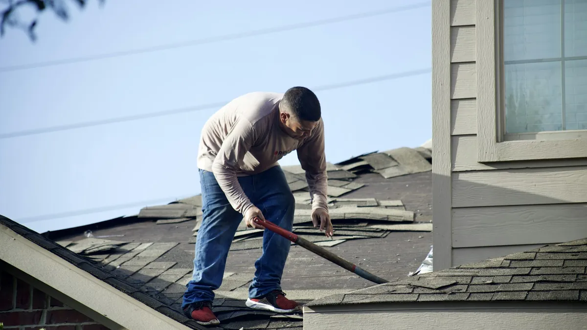 Roofer removing shingles during a residential roof replacement