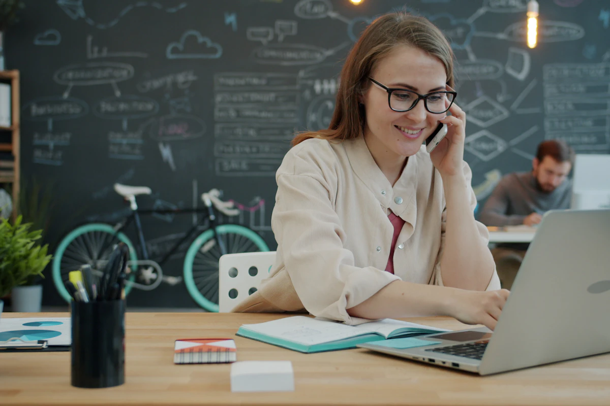 Person answering a phone call while working at a laptop