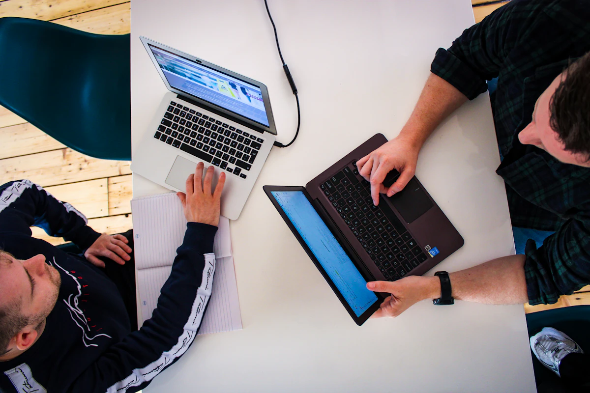 Two people reviewing work together on laptops